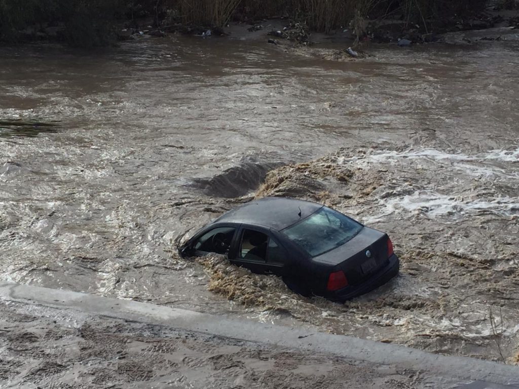 Auto vuelca y es arrastrado por la corriente en la canalización