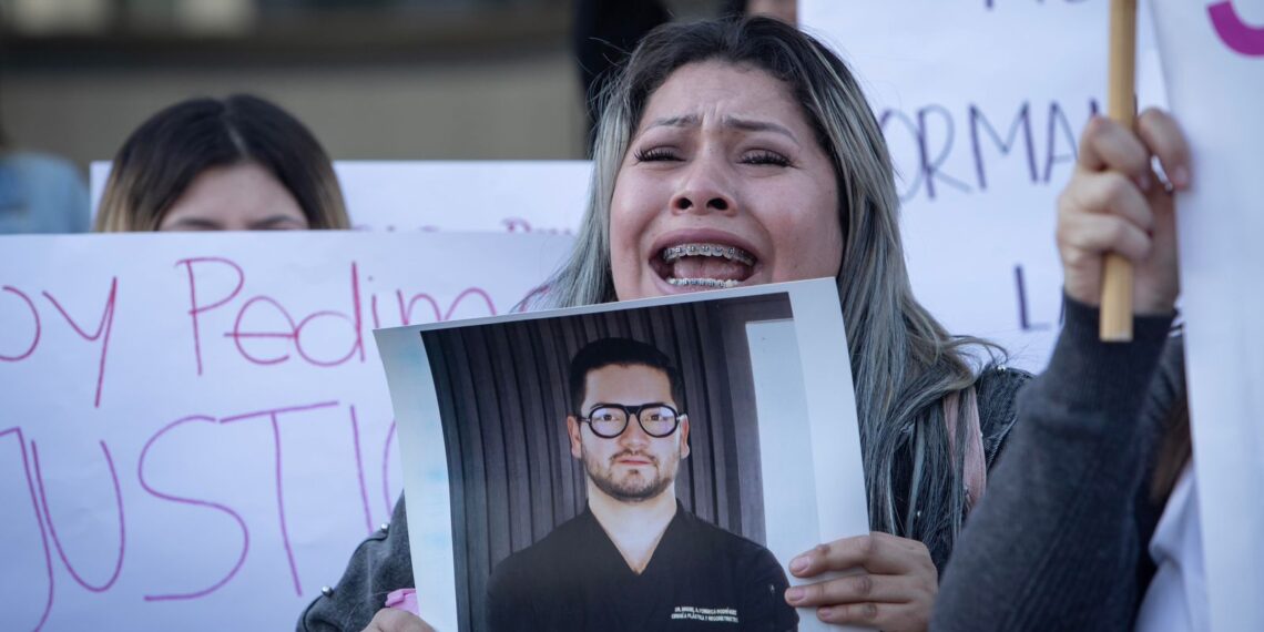 Woman holding a photo and shouting at a protest.