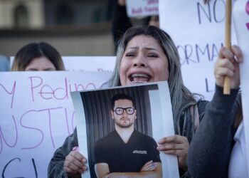 Woman holding a photo and shouting at a protest.